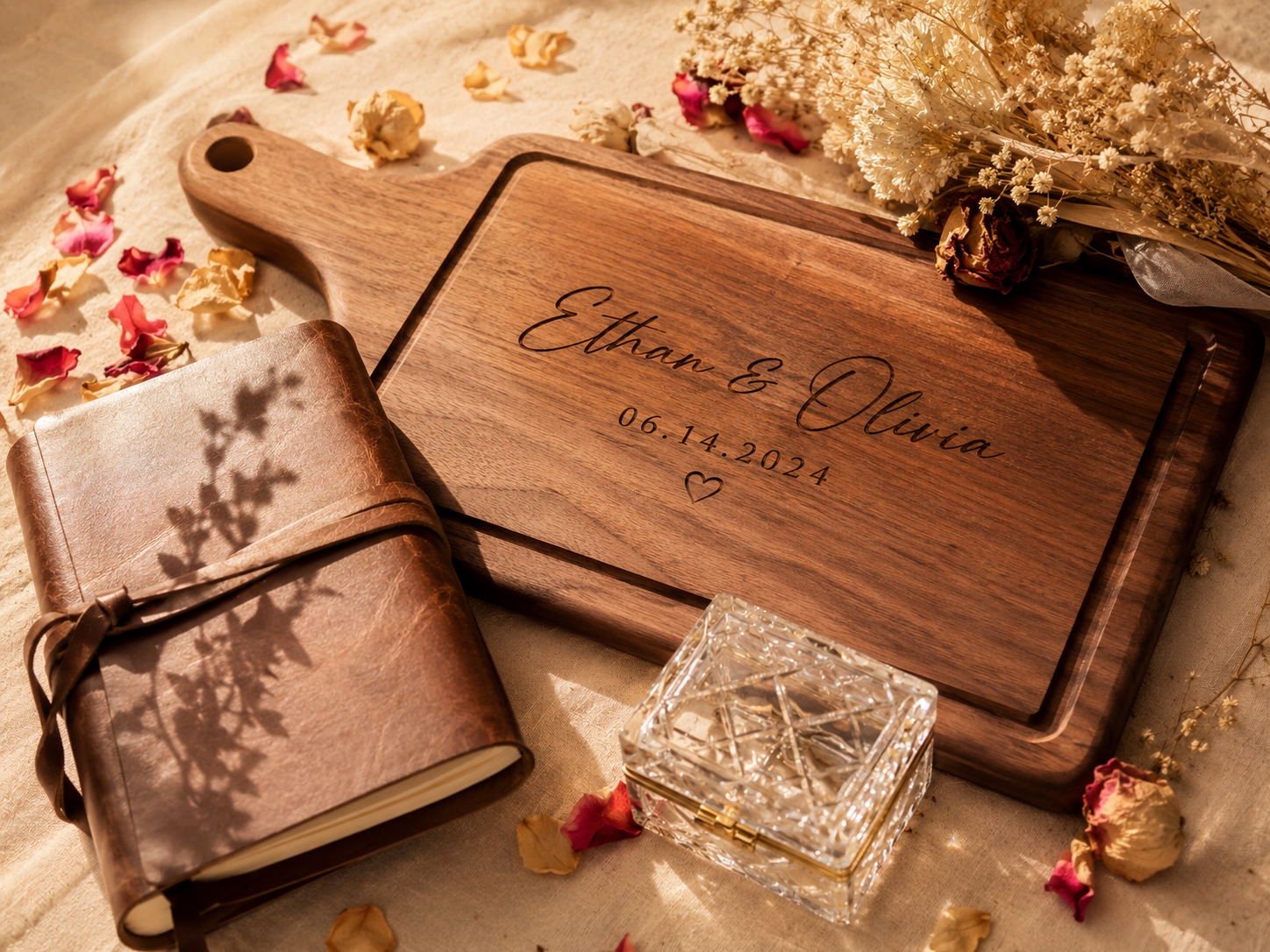 Flat-lay on a rustic wood table showing a small collection of anniversary-themed items arranged by material: a leather-bound journal